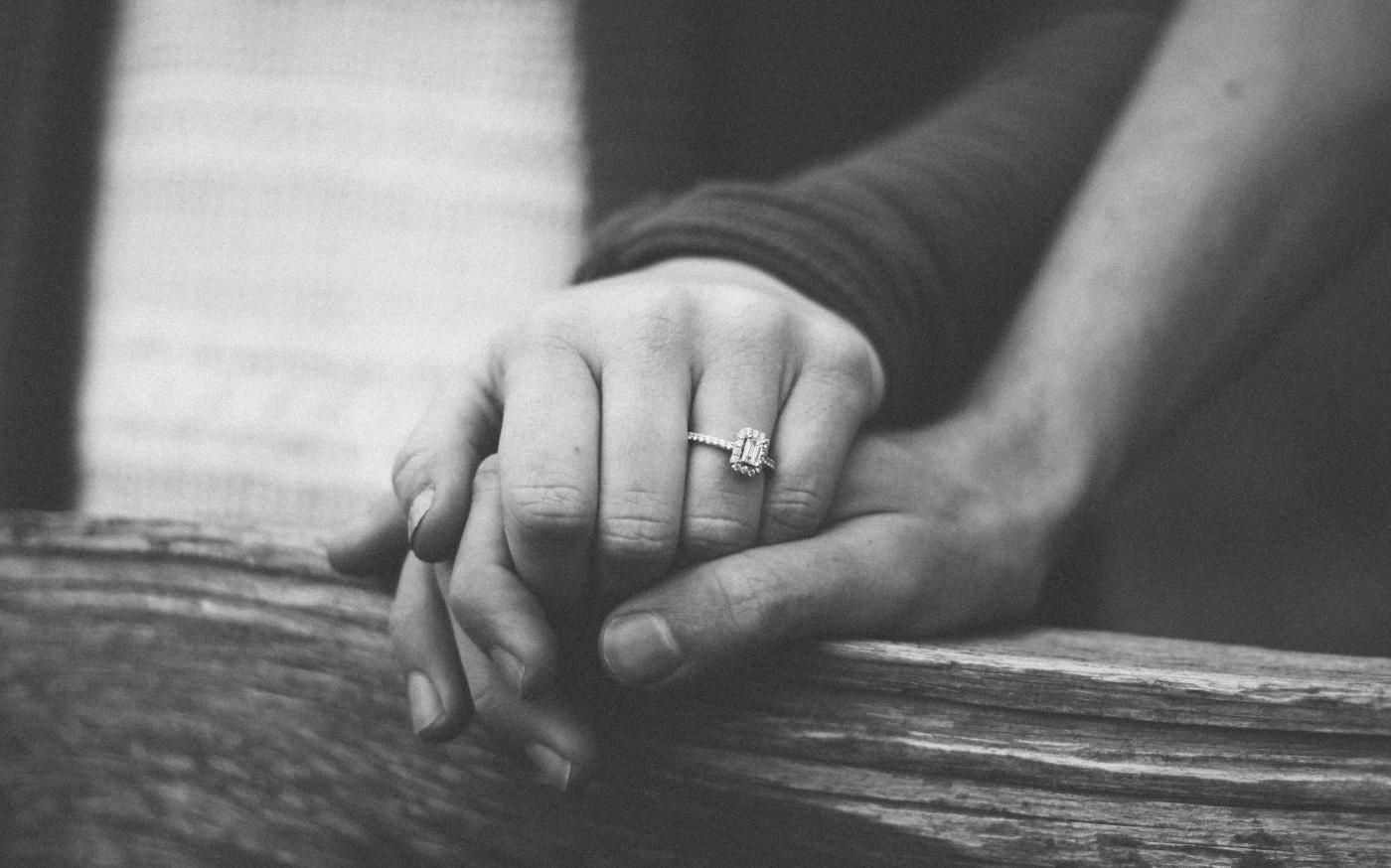 a couple holding hands with a wedding ring visible by Shelby Deeter courtesy of Unsplash.