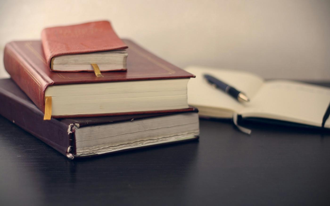 selective focus photography of three books beside opened notebook by Mikhail Pavstyuk courtesy of Unsplash.