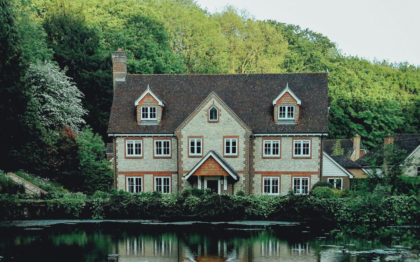 concrete house near a body of water and forest by Evelyn  Paris courtesy of Unsplash.
