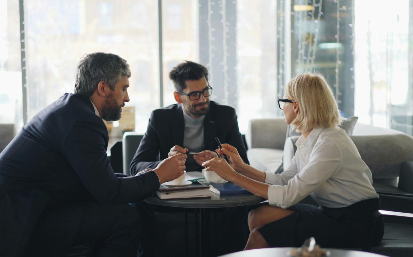 a group of people sitting around a table by Vitaly Gariev courtesy of Unsplash.