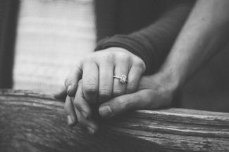 a couple holding hands with a wedding ring visible by Shelby Deeter courtesy of Unsplash.