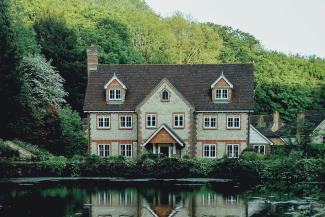 concrete house near a body of water and forest by Evelyn  Paris courtesy of Unsplash.
