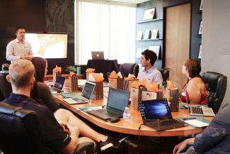 man standing in front of people sitting beside table with laptop computers by Campaign Creators courtesy of Unsplash.