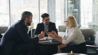 a group of people sitting around a table by Vitaly Gariev courtesy of Unsplash.