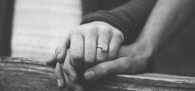 a couple holding hands with a wedding ring visible by Shelby Deeter courtesy of Unsplash.