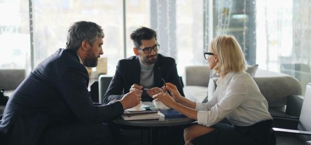 a group of people sitting around a table by Vitaly Gariev courtesy of Unsplash.