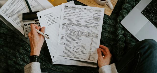 Person reviewing documents with calculator and laptop. by Kelly Sikkema courtesy of Unsplash.